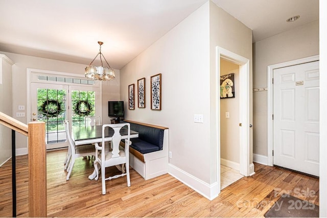 dining space with light wood-style floors, baseboards, and an inviting chandelier