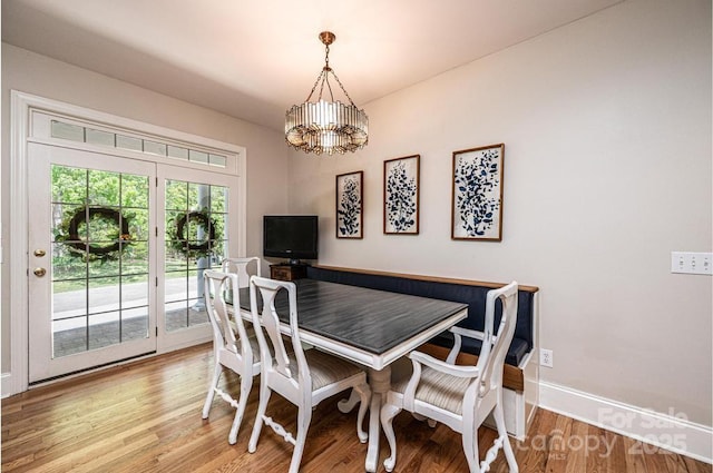 dining room featuring baseboards, light wood finished floors, and a chandelier