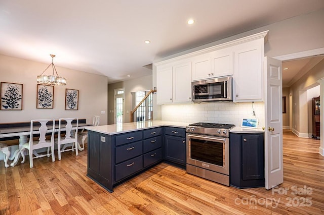 kitchen featuring light countertops, appliances with stainless steel finishes, white cabinets, and a peninsula