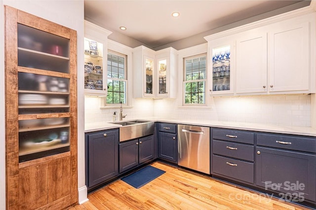bar featuring decorative backsplash, stainless steel dishwasher, a sink, recessed lighting, and light wood-style flooring
