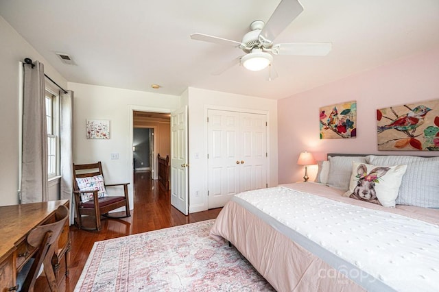 bedroom featuring visible vents, a ceiling fan, dark wood-type flooring, and a closet