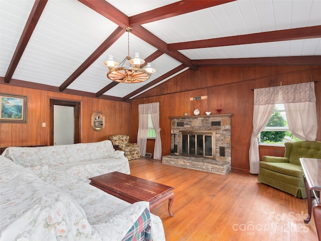 living area featuring lofted ceiling with beams, a fireplace, wood walls, a chandelier, and wood finished floors
