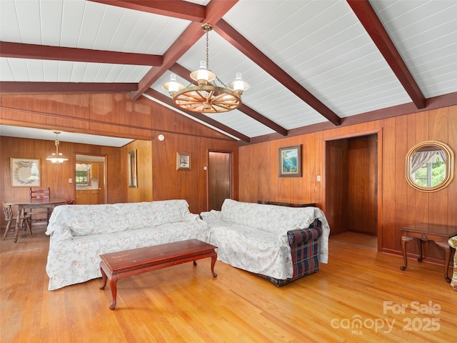 living area featuring lofted ceiling with beams, wood finished floors, a notable chandelier, and wood walls