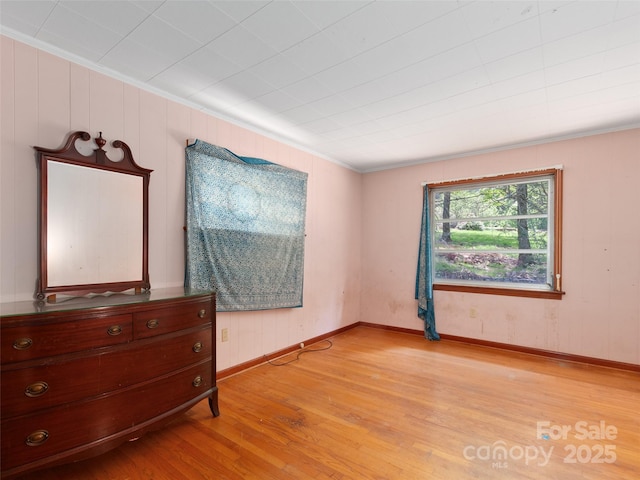 bedroom with baseboards, ornamental molding, and light wood-style flooring