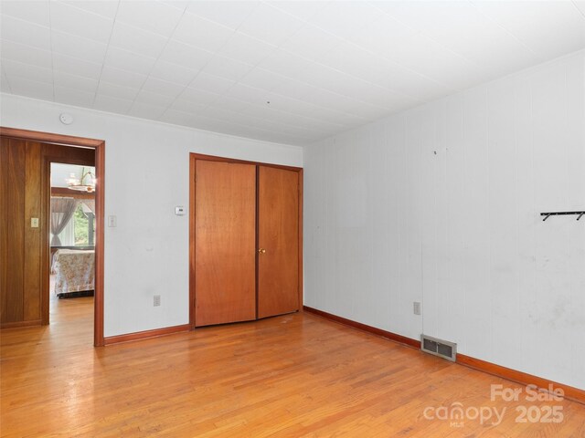 unfurnished bedroom featuring visible vents, baseboards, a closet, and light wood-type flooring