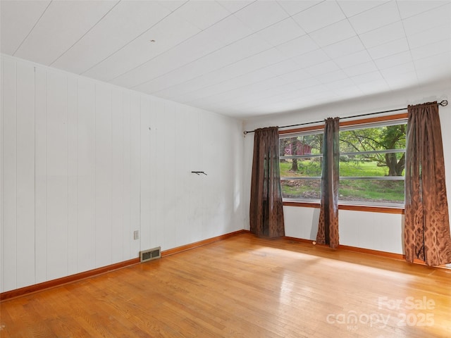 empty room featuring baseboards, light wood finished floors, and visible vents
