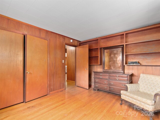 living area with light wood-style floors and wood walls