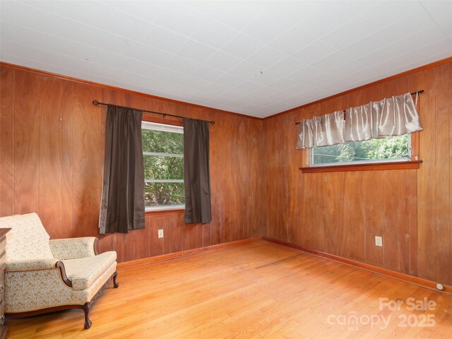 living area with baseboards, wood walls, and wood finished floors