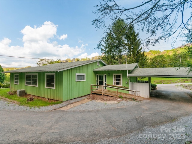 view of front of house with roof with shingles, cooling unit, and aphalt driveway