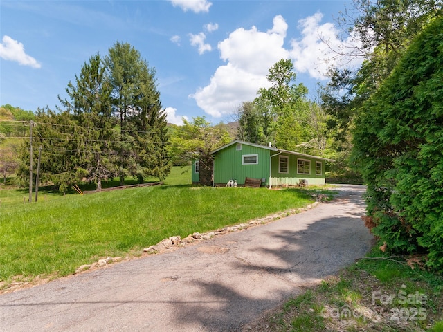 view of side of property with a lawn and aphalt driveway