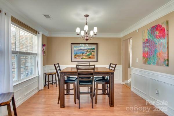 136 Elba Dr, Mooresville, NC 28115 - dining room featuring a chandelier, a decorative wall, healthy amount of natural light, light wood-style flooring, and ornamental molding