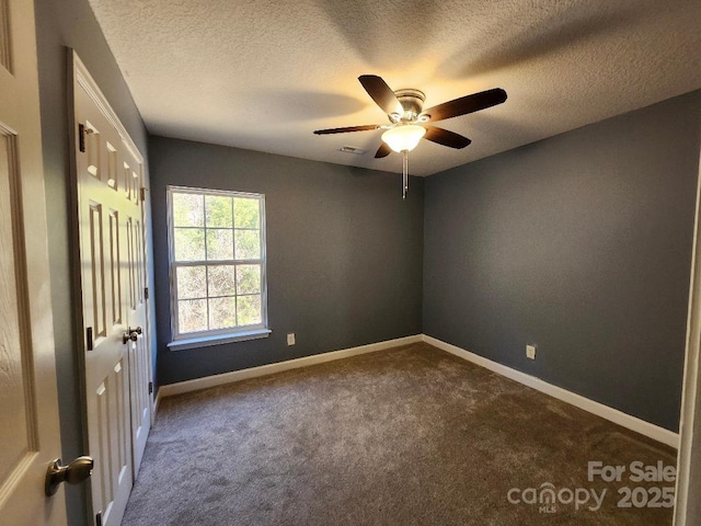 spare room with dark colored carpet, ceiling fan, baseboards, and a textured ceiling