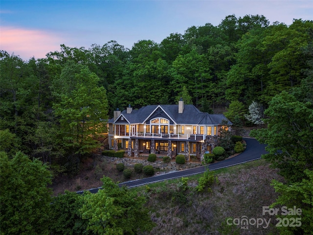 714 Wickhams Fancy Dr, Biltmore Lake, NC 28715 - back of property at dusk featuring a wooded view, a deck, a chimney, and driveway