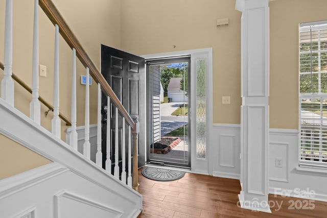 foyer featuring stairs, wainscoting, ornate columns, and wood finished floors