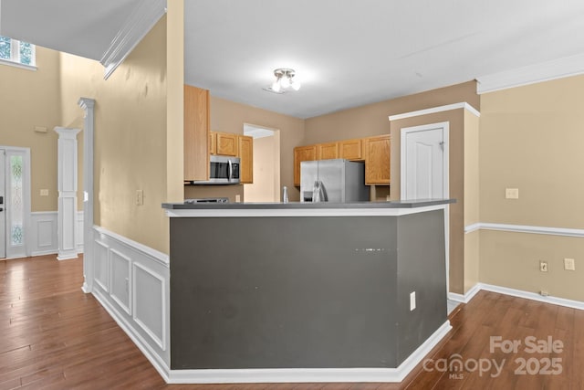 kitchen featuring a peninsula, dark wood finished floors, appliances with stainless steel finishes, and a wainscoted wall