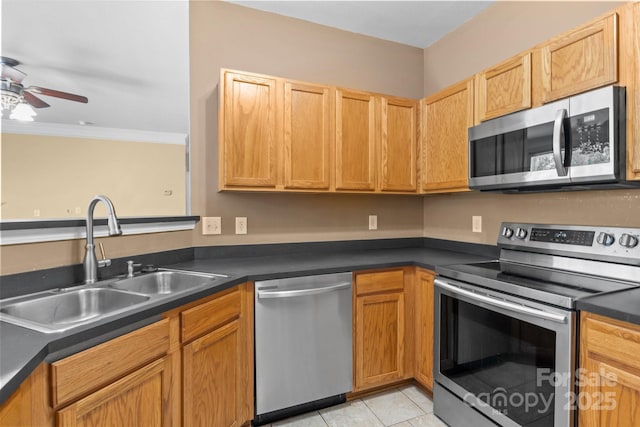 kitchen featuring ceiling fan, appliances with stainless steel finishes, dark countertops, a sink, and light tile patterned floors