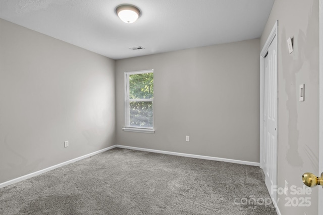 spare room with visible vents, carpet, and baseboards