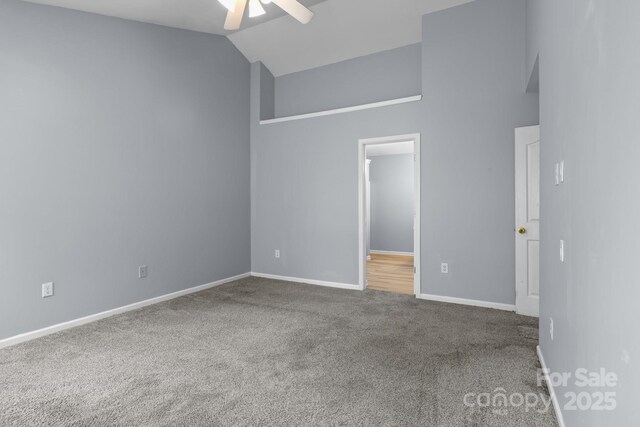 empty room featuring carpet flooring, ceiling fan, baseboards, and high vaulted ceiling