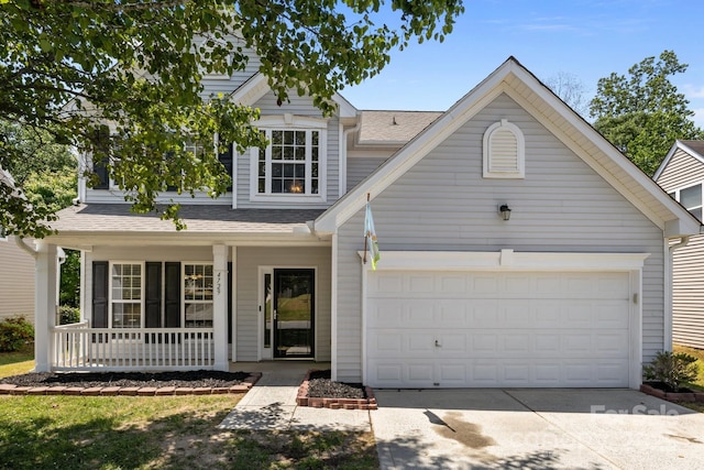 traditional-style home featuring a garage, covered porch, driveway, and a shingled roof