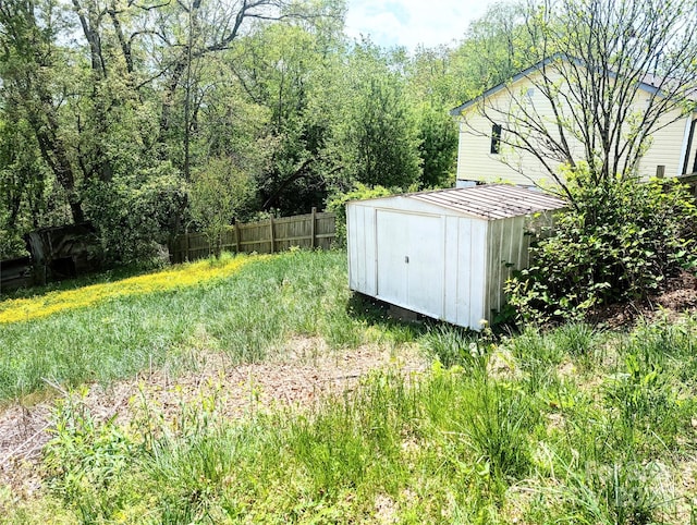 view of yard featuring a storage shed, fence, and an outdoor structure
