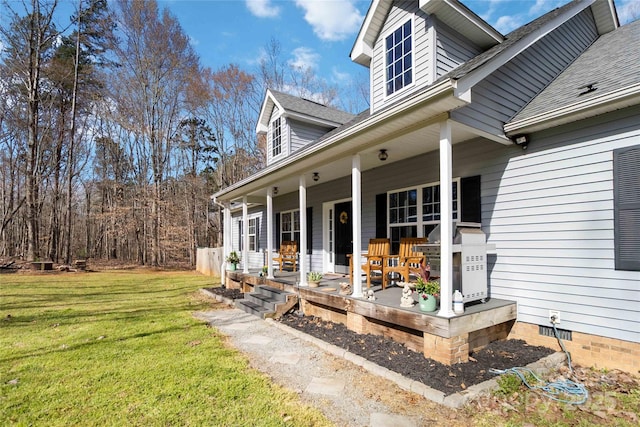 exterior space with roof with shingles, covered porch, a yard, and crawl space