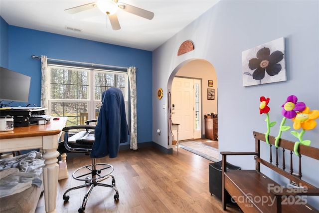 office space with visible vents, arched walkways, ceiling fan, and wood finished floors