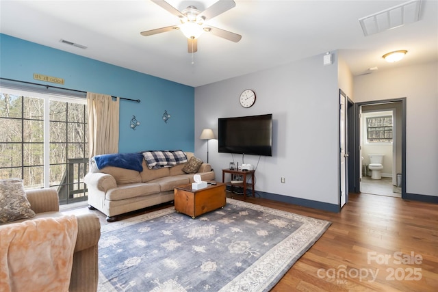 living room with baseboards, a ceiling fan, wood finished floors, and visible vents