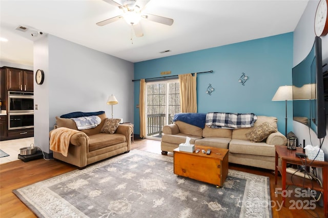living area featuring light wood-style floors, a ceiling fan, and visible vents