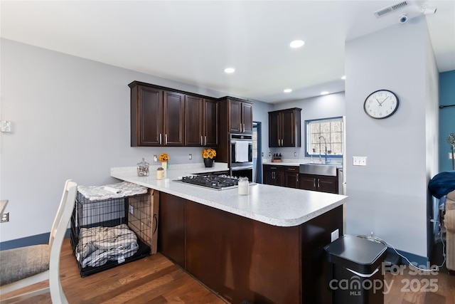kitchen with visible vents, a peninsula, light countertops, a sink, and appliances with stainless steel finishes