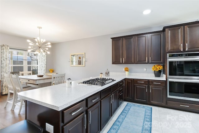 kitchen featuring light countertops, appliances with stainless steel finishes, and dark brown cabinets