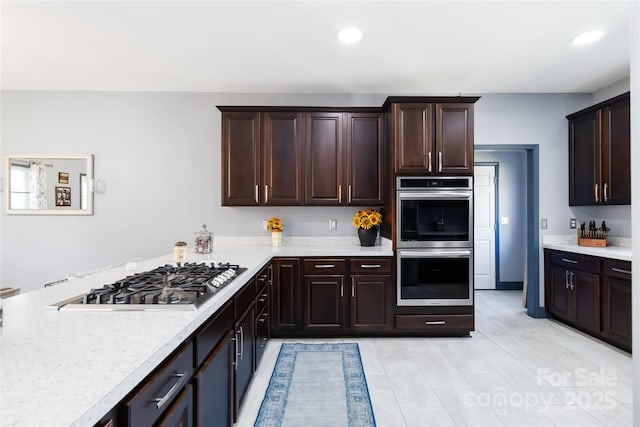 kitchen with light countertops, dark brown cabinetry, and stainless steel appliances