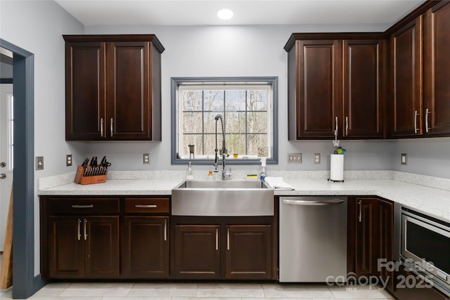 kitchen with a sink, appliances with stainless steel finishes, light tile patterned floors, and dark brown cabinets