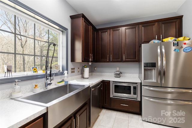kitchen with light countertops, a sink, appliances with stainless steel finishes, and light tile patterned floors
