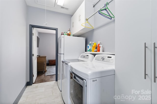 laundry room featuring visible vents, baseboards, attic access, separate washer and dryer, and cabinet space