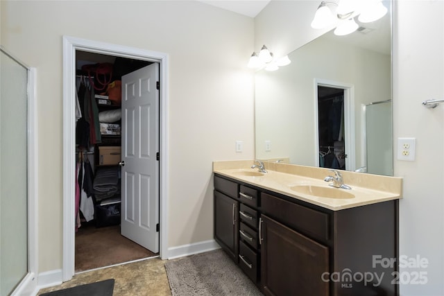 bathroom featuring a sink, an enclosed shower, double vanity, and a spacious closet
