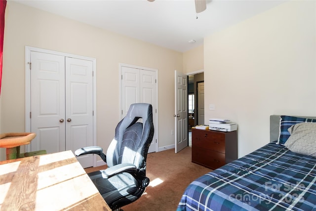 carpeted bedroom featuring baseboards, ceiling fan, and multiple closets