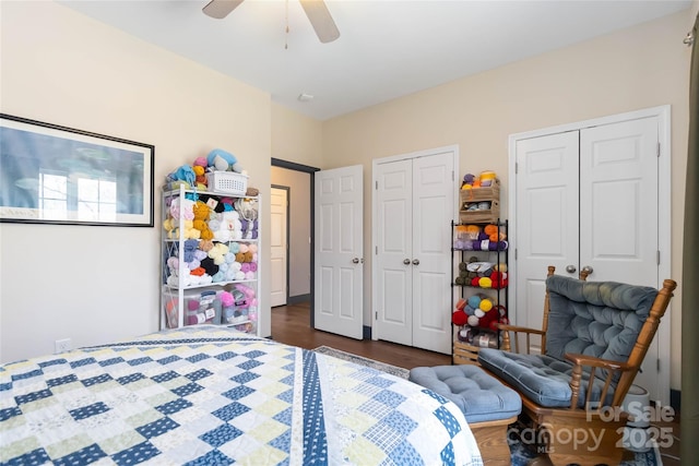 bedroom featuring a ceiling fan, multiple closets, and dark wood-style floors