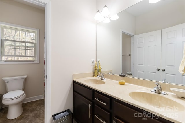bathroom with double vanity, a sink, baseboards, and toilet