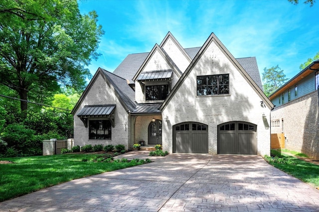 view of front of property with an attached garage, brick siding, a front yard, decorative driveway, and a standing seam roof