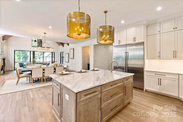 kitchen with lofted ceiling, light stone countertops, built in refrigerator, white cabinets, and light wood-style flooring