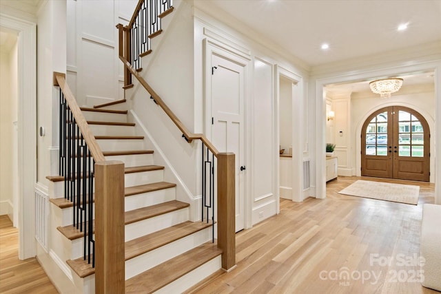 foyer entrance featuring an inviting chandelier, light wood-style floors, stairway, recessed lighting, and french doors