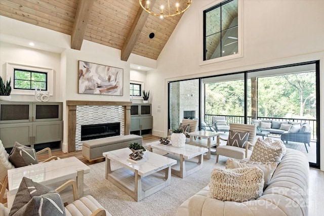 living area featuring high vaulted ceiling, a chandelier, a tiled fireplace, wooden ceiling, and light wood-type flooring