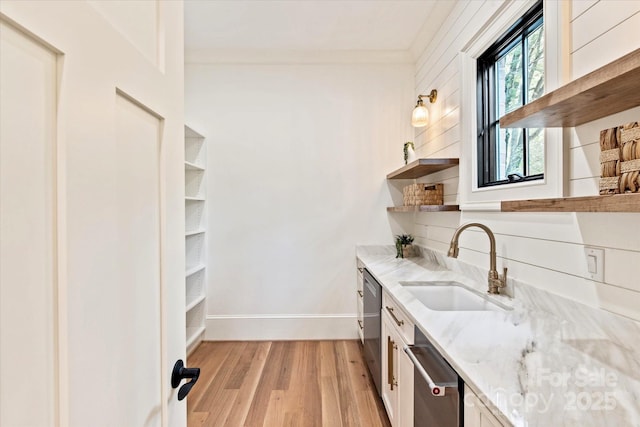 interior space featuring a sink, baseboards, light wood-style floors, and dishwasher
