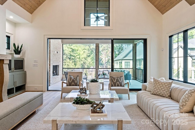living area with high vaulted ceiling, baseboards, and wood ceiling