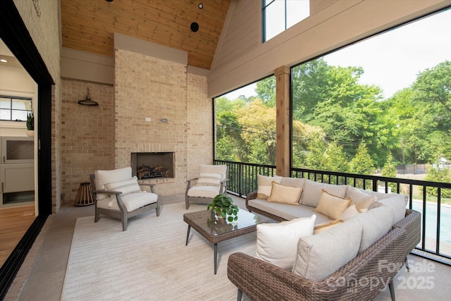 sunroom / solarium with plenty of natural light and an outdoor living space with a fireplace