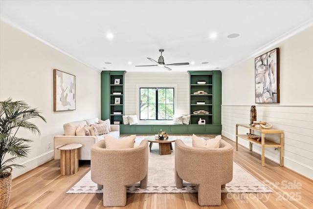 living area featuring ceiling fan, ornamental molding, and light wood finished floors