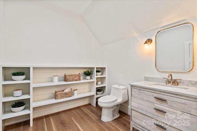 bathroom with toilet, vaulted ceiling, wood finished floors, and vanity