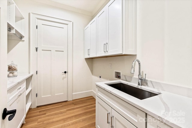 laundry area featuring washer hookup, hookup for an electric dryer, cabinet space, a sink, and light wood finished floors