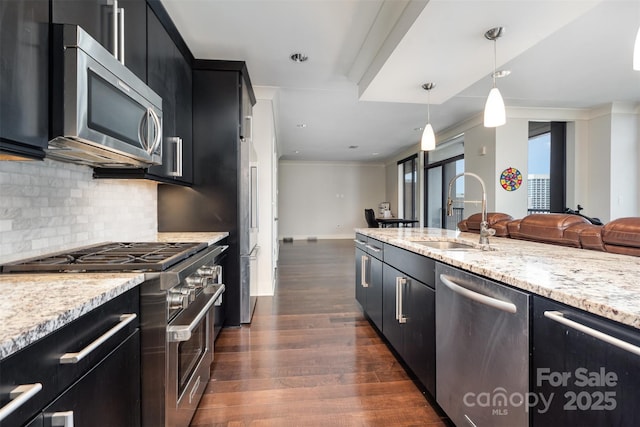 kitchen featuring appliances with stainless steel finishes, a sink, dark wood-style floors, open floor plan, and dark cabinetry