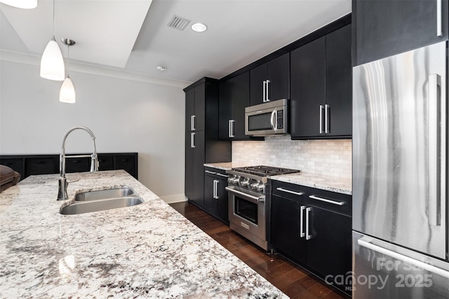 kitchen featuring hanging light fixtures, tasteful backsplash, a sink, dark cabinets, and stainless steel appliances